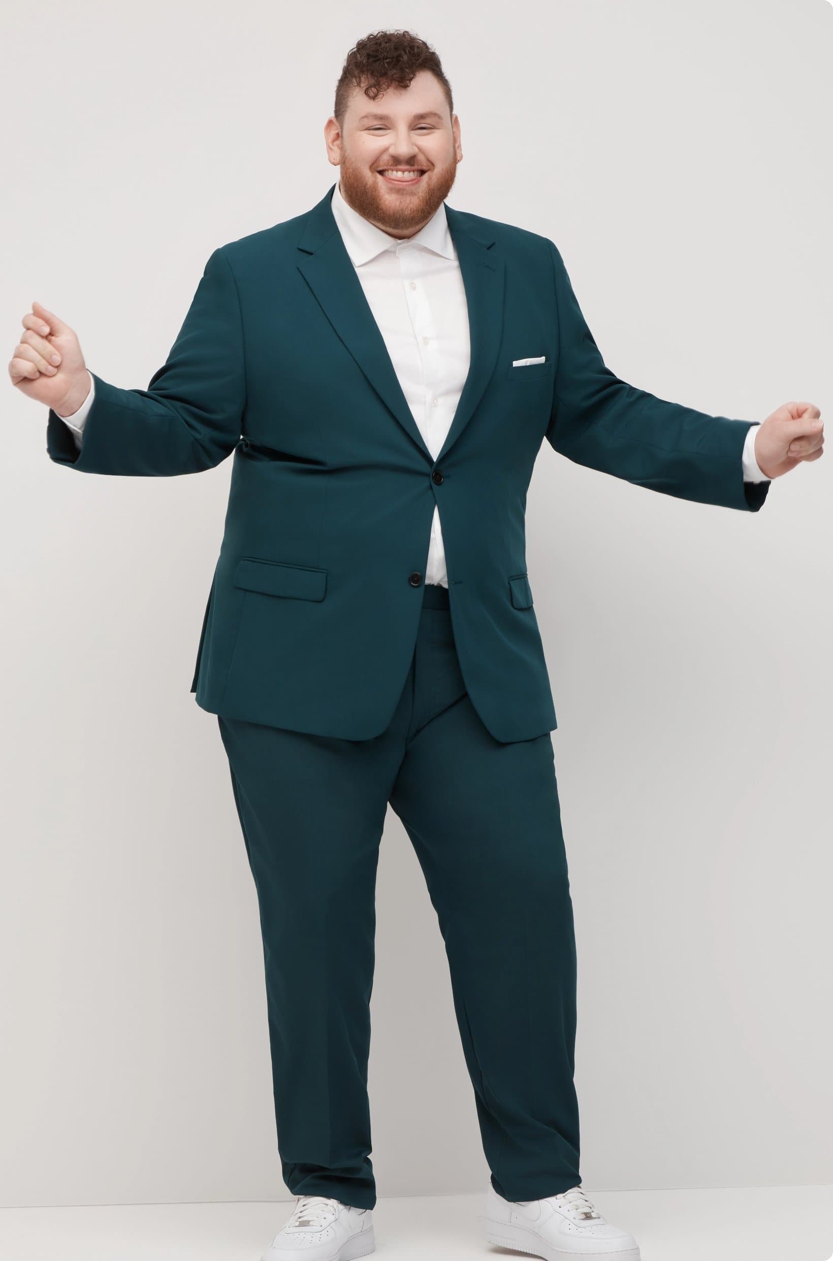Plus size man smiling and dancing in big and tall dark gray suit and modern styling.
