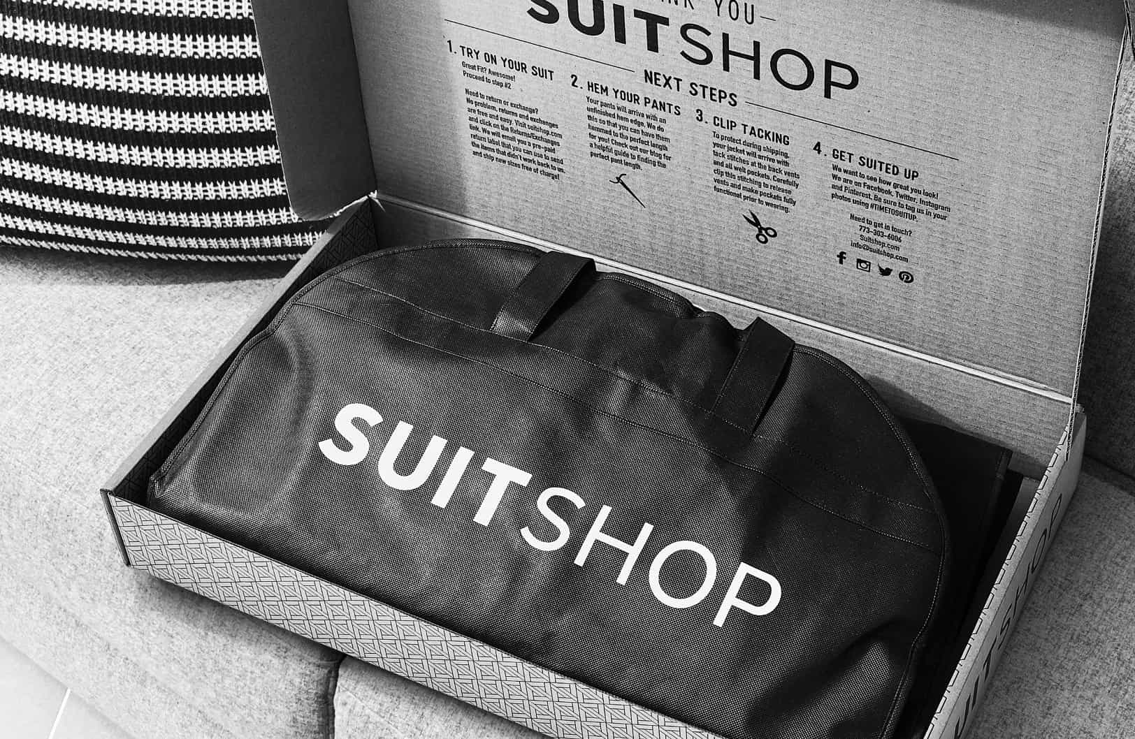 SuitShop delivery box open showing written next steps and suit garment bag in black and white.