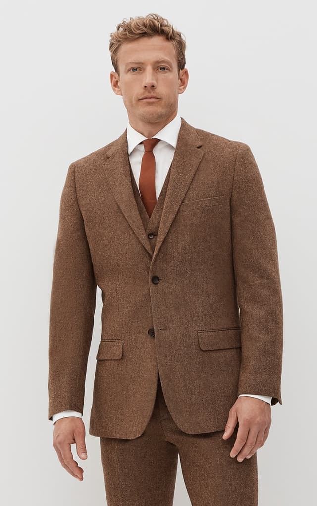 Man wearing brown tweed suit with a clay tie.