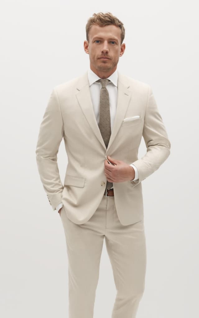 Man wearing tan suit with a brown tie.